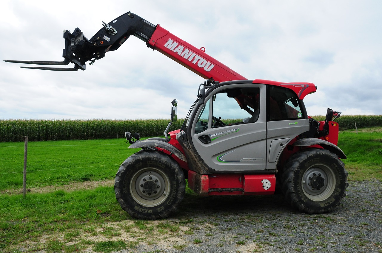 Red and white telehandler forklift in a field, representing Rhino Industrial Forklifts equipment